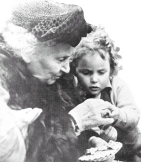 black and white photograph of elderly Dr. Montessori interacting with a young child